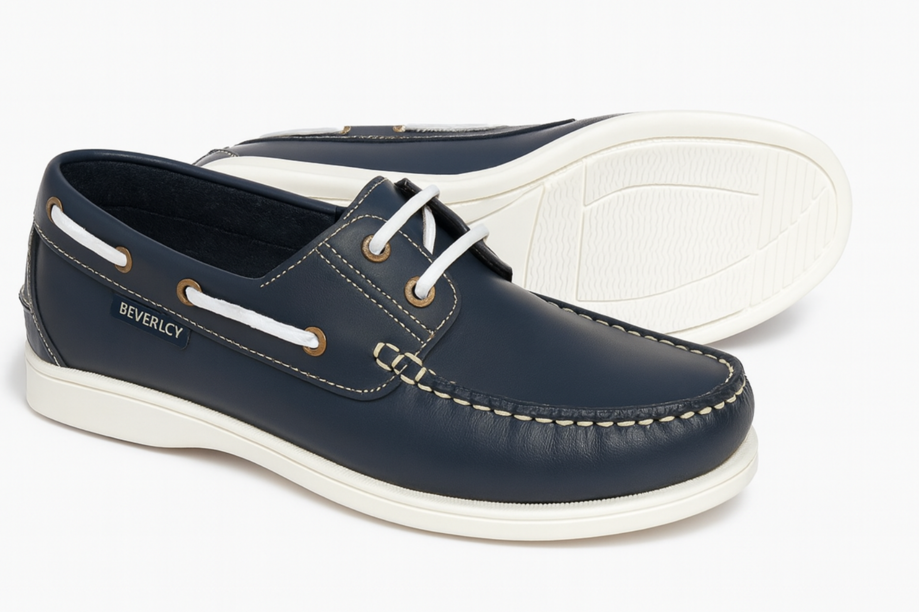 Pair of navy blue boat shoes with white soles on a light gray background