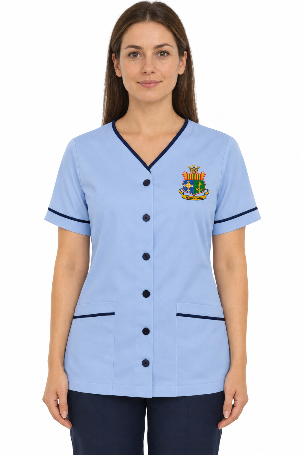 A woman modeling a light blue short-sleeve scrub top with dark navy trim, a button-front closure, and a small embroidered medical-style crest on the left chest, against a plain white background.